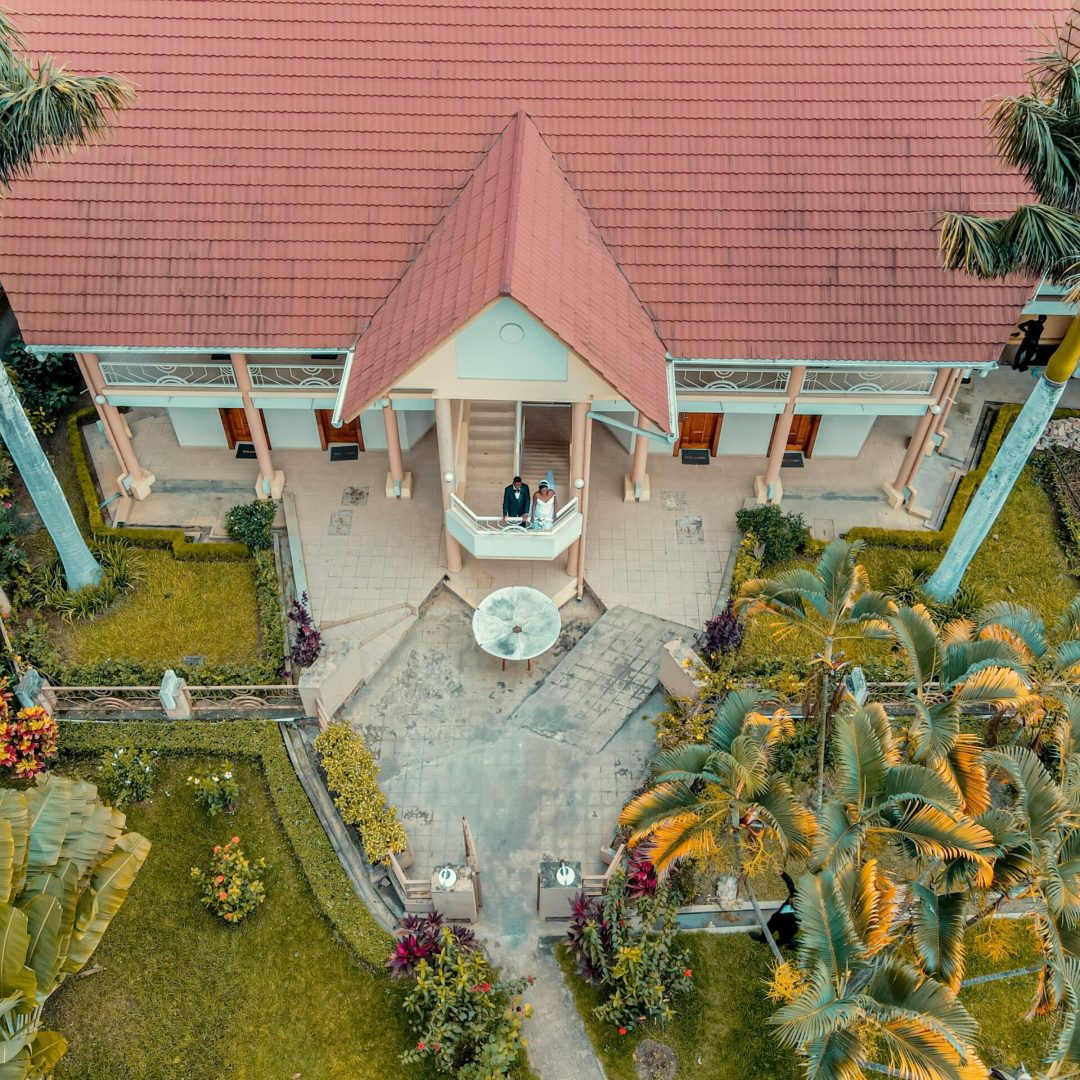 Aerial shot of a beautiful tropical building with a red roof, surrounded by lush greenery.